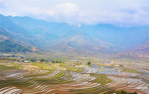 Những thửa ruộng loang loáng nước trải dài dưới chân những ngọn núi cao xanh tím, bên trên là mây trắng vờn quanh